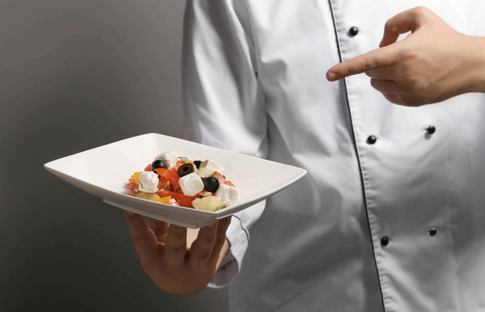 Chef arranging plated tasting menu on textured plate